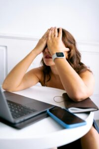 Erschöpfte Frau vor Laptop mit müdem Gesichtsausdruck